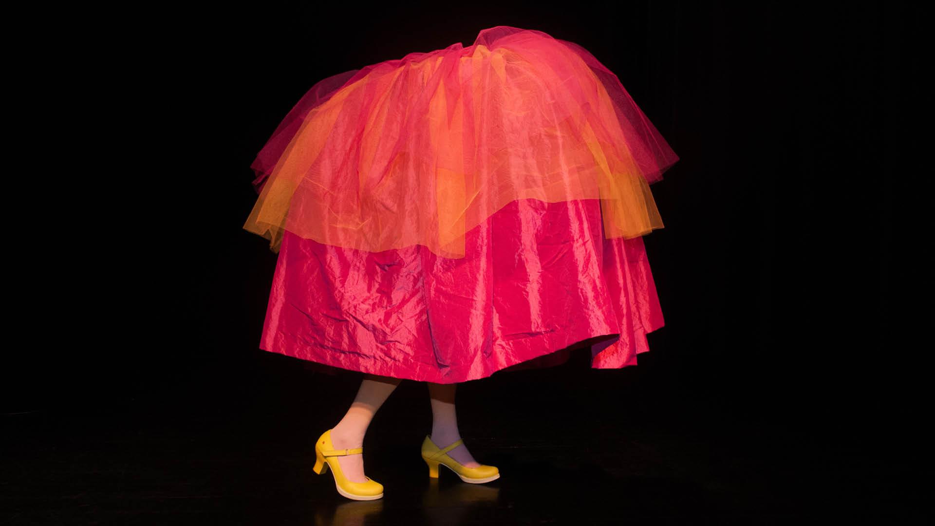 Stor kjol i rosa och orange med två fötter som sticker ut