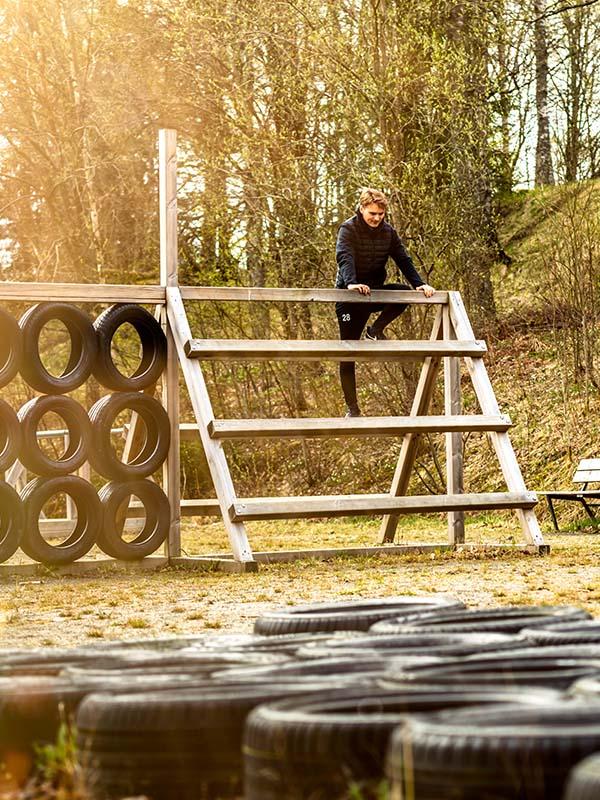 Kille klättrar över hinder på utegym