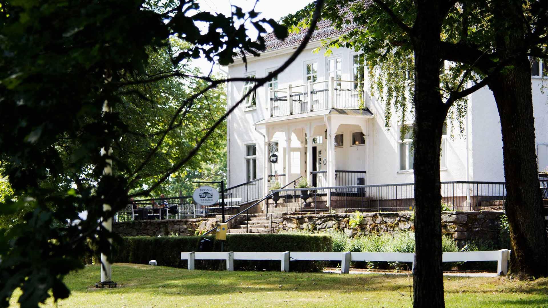 En vit herrgård omgiven av lummig skog.