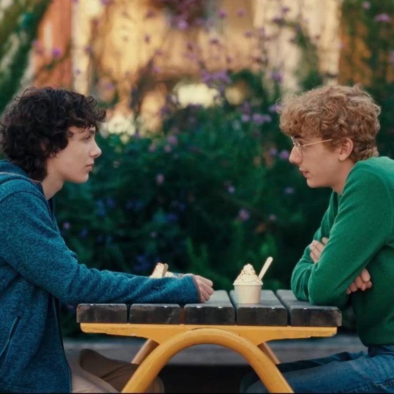 Två killar sitter mitt emot varande på en parkbänk.