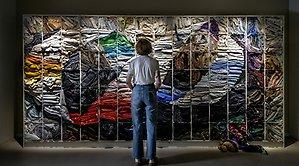 person står med ryggen till framför ett textilt konstverk