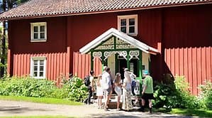 Personer utanför en gammal träbyggnad i rött