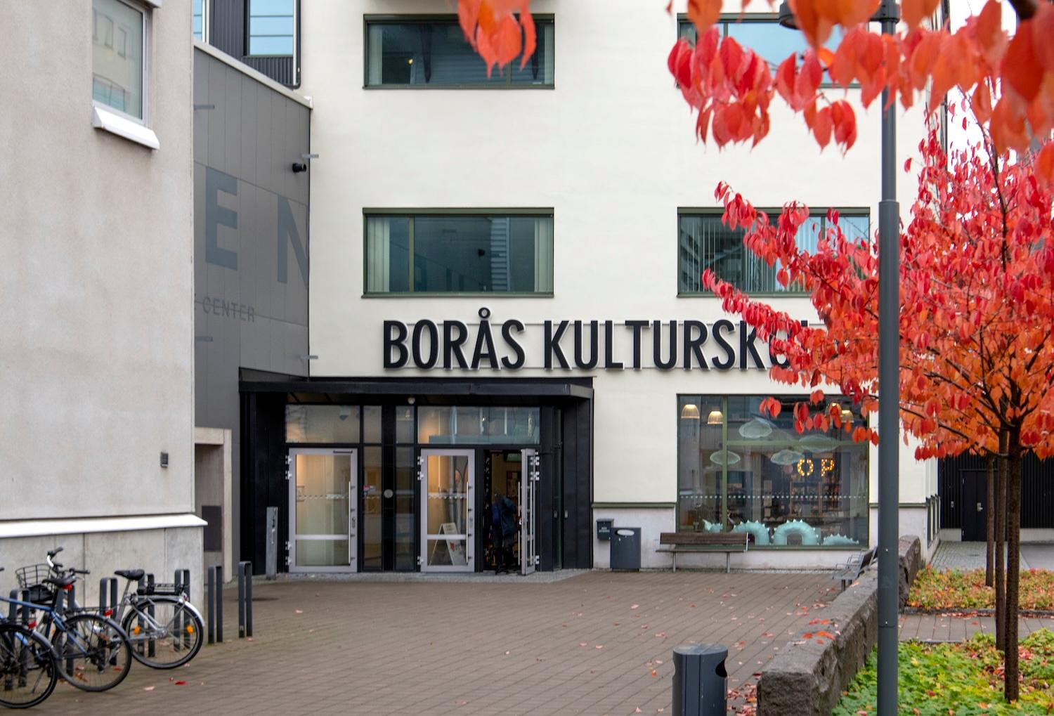 Bild på Borås Kulturskolas entré med röda höstlöv i förgrunden.