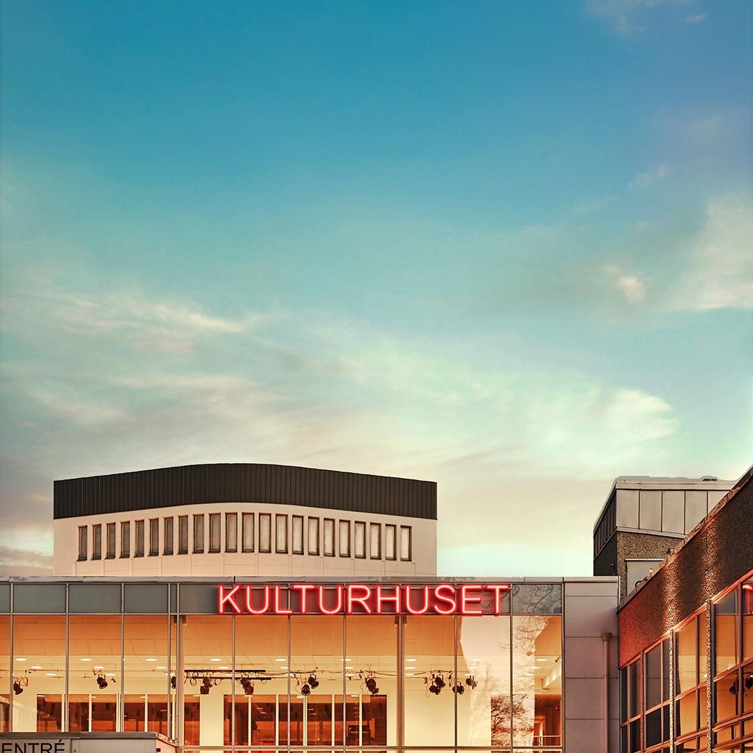 Byggnade med neonskylt "Kulturhuset" på, blå solig himmel.