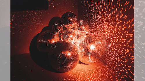 Discobollar som reflekterar rödaktigt ljus på väggen.