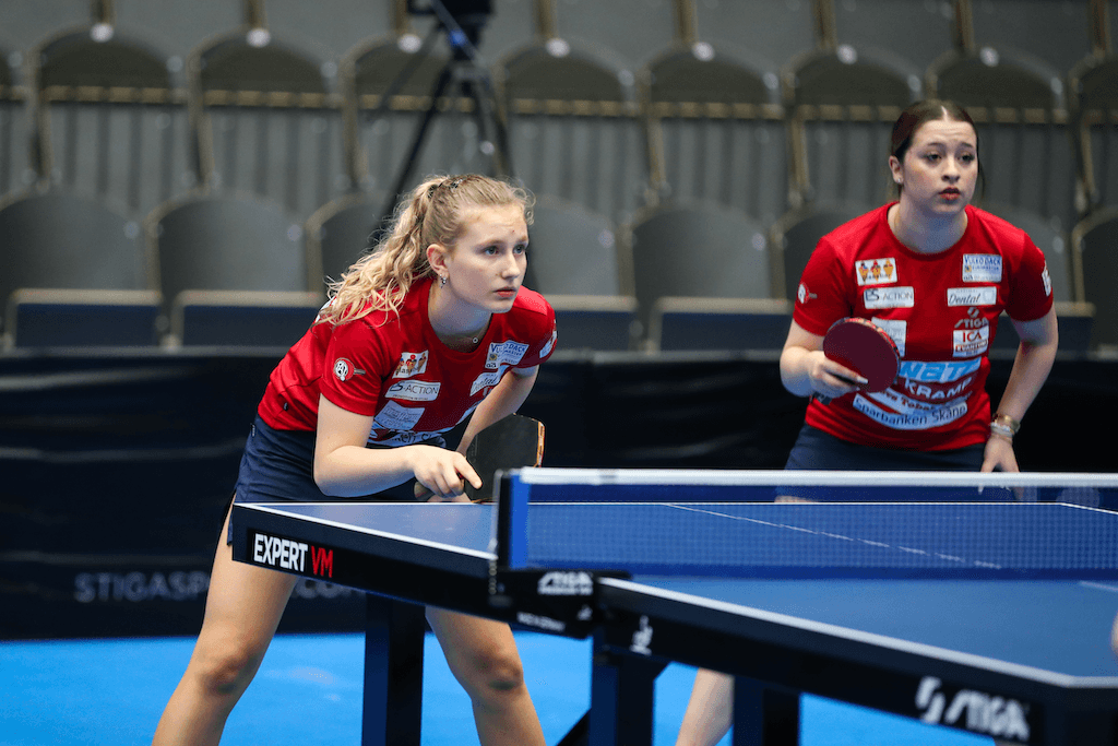 Två tjejer spelar bordtennis.