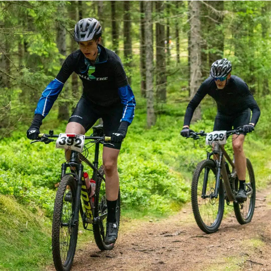 två cyklister på en stig i skogen