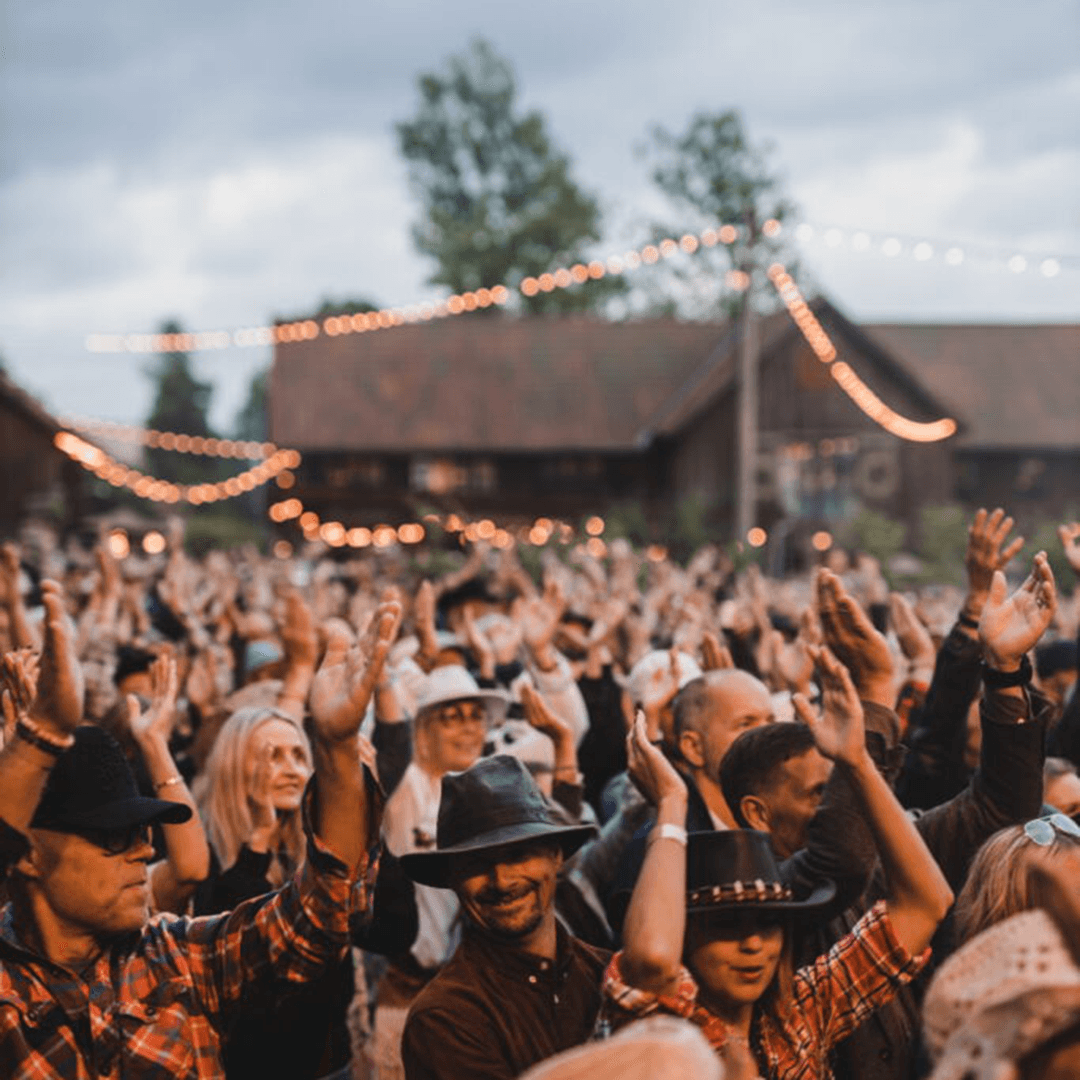 glada människor med countrykläder vid en scen
