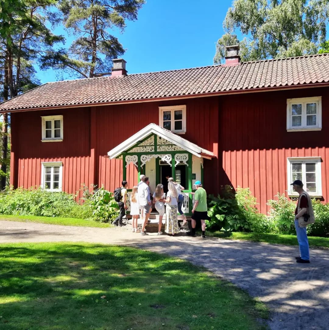 Personer utanför en gammal träbyggnad i rött