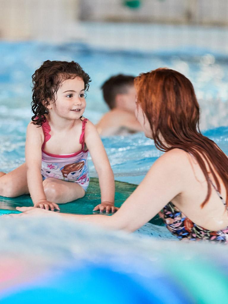 ett barn med sin mamma i en pool