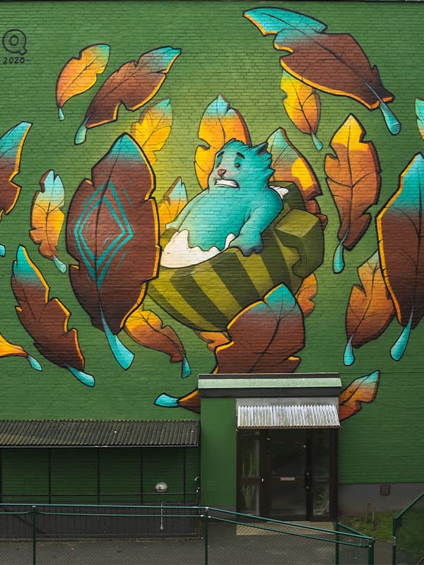 Muralmålning av ett sagoväsen med bruna löv omkring sig
