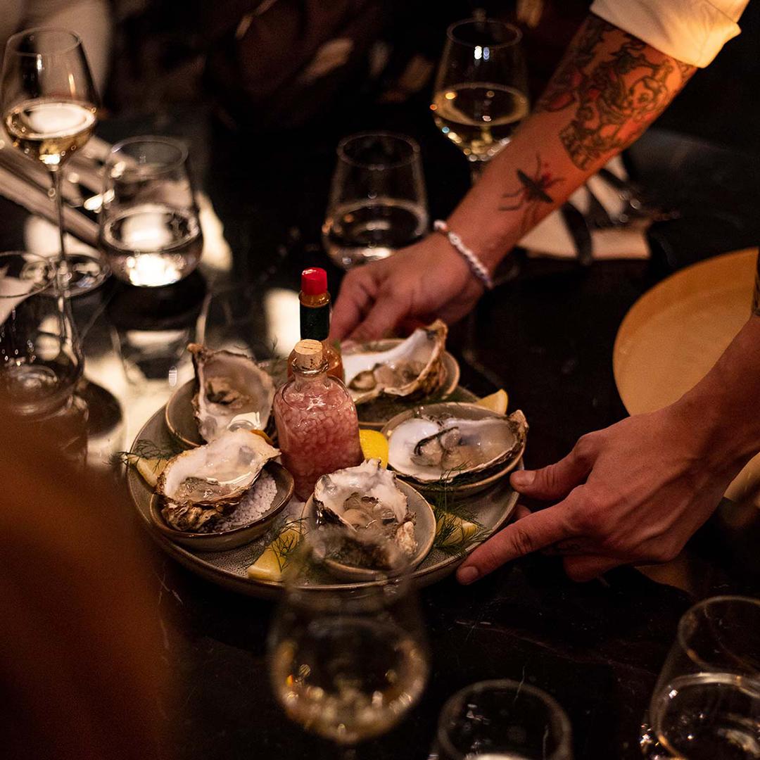 En servitör serverar ostron på en bricka.