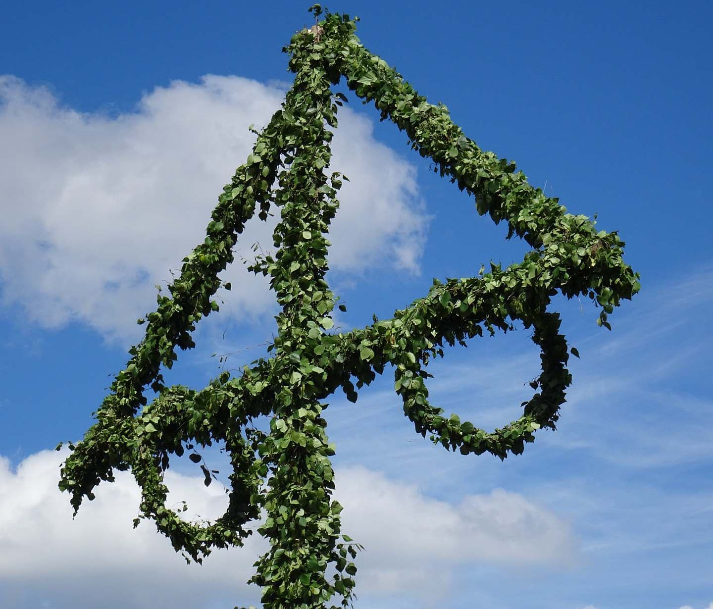 En midsommarstång mot en blå himmel.