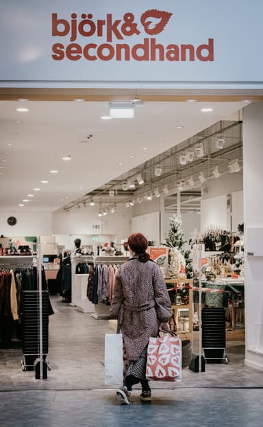 En kvinna går in i en butik med påsar i handen.