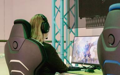 En tjej sitter framför en dator och gejmar..