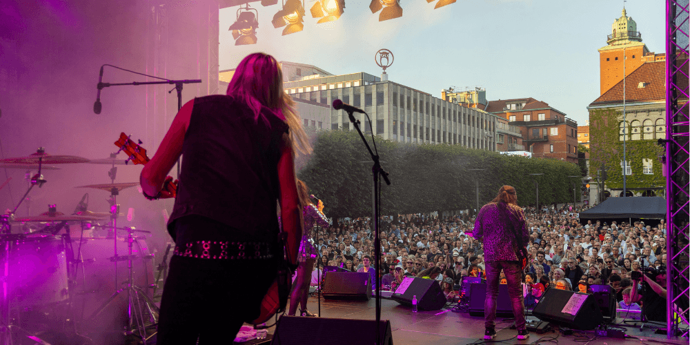 Ett band spelar musik framför ett torg fyllt av folk.