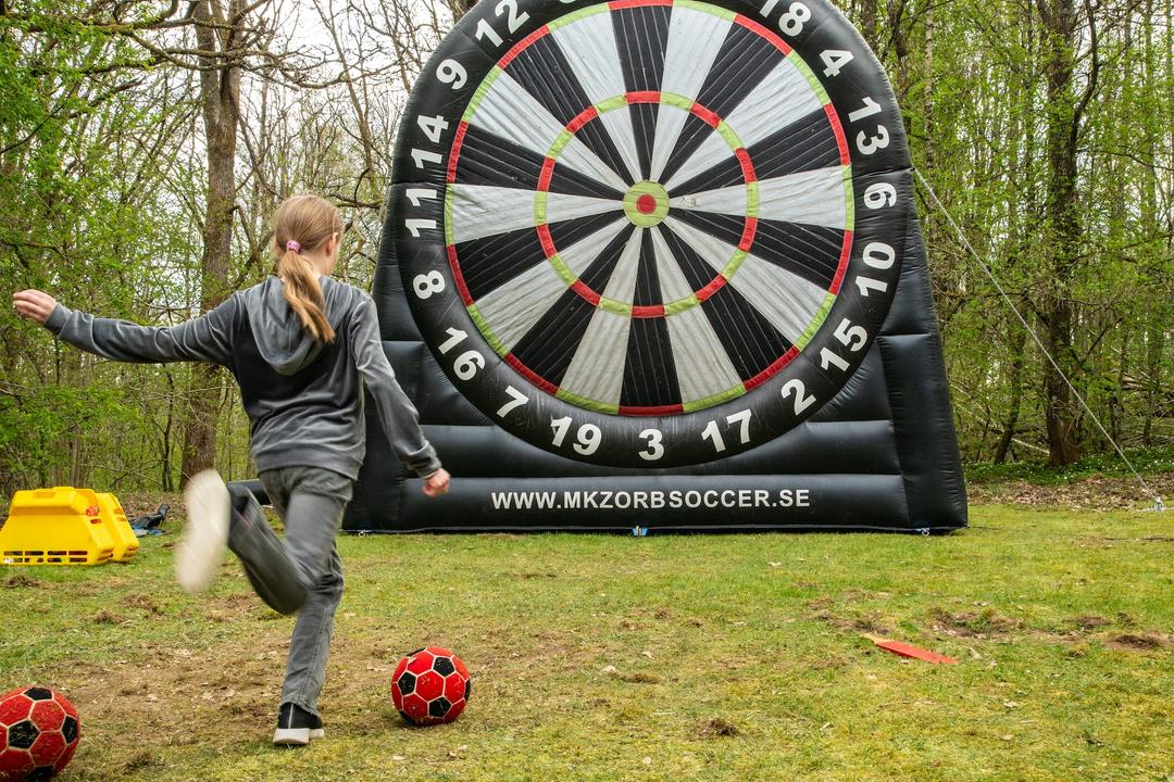 En tjej sparkar boll framför en stor darttavla.