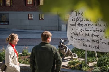 Två personer tittar på ett konstverk ute på stan.