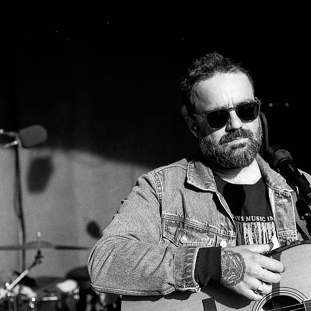 svartvit bild, en man i jeansjacka och en gitarr