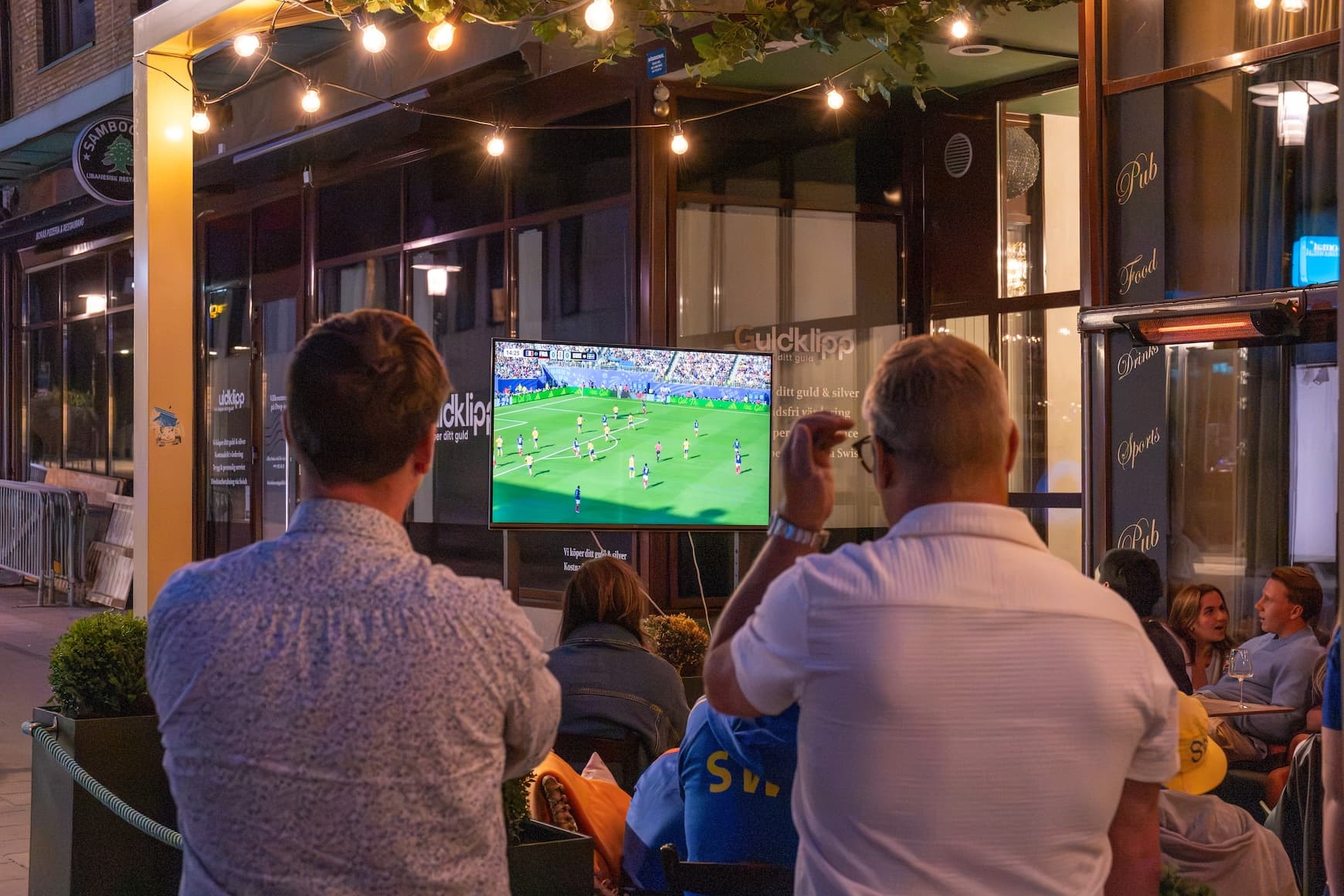 Två män tittar på fotboll på en TV.