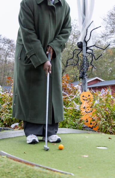 En kvinna i en grön kappa spelar golf.