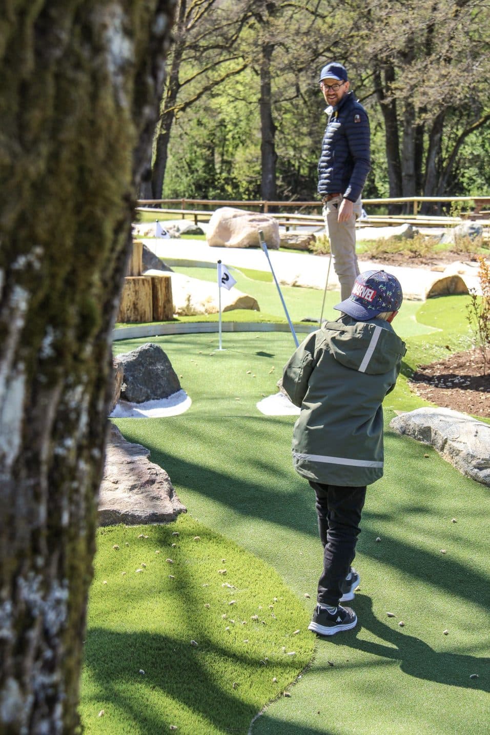 Äventyrsgolfbana en liten kille svingar golfklubban.