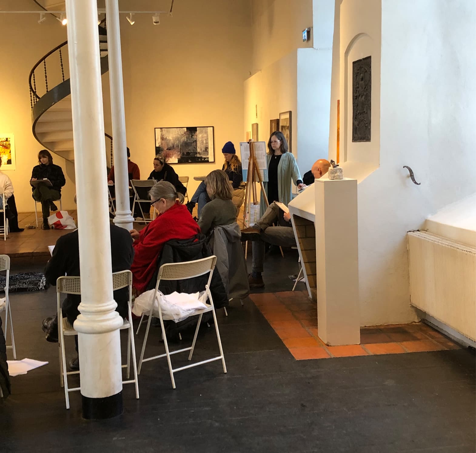 En bild med människors ryggar och de befinner sig i ett konstgalleri